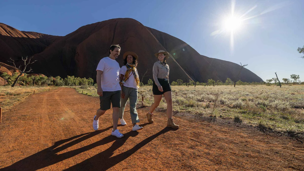 Small group pausing at a cave with rock art on a guided trek around the base of Uluru, Uluru-Kata Tjuta National Park Australia